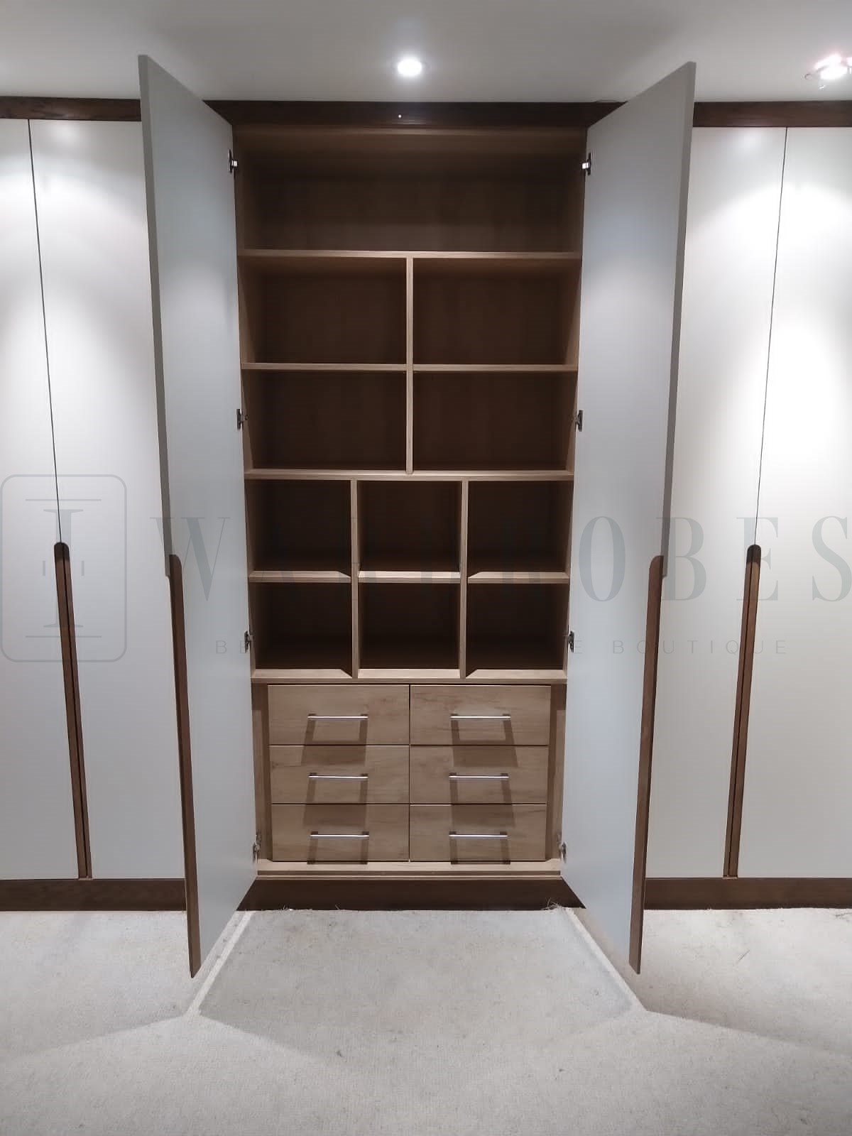 Bespoke white spray painted wardrobe with wooden handles and internal compartments.