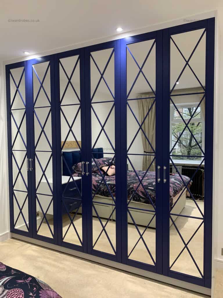 Bespoke navy blue painted fretwork mirror wardrobe with mirrored doors.