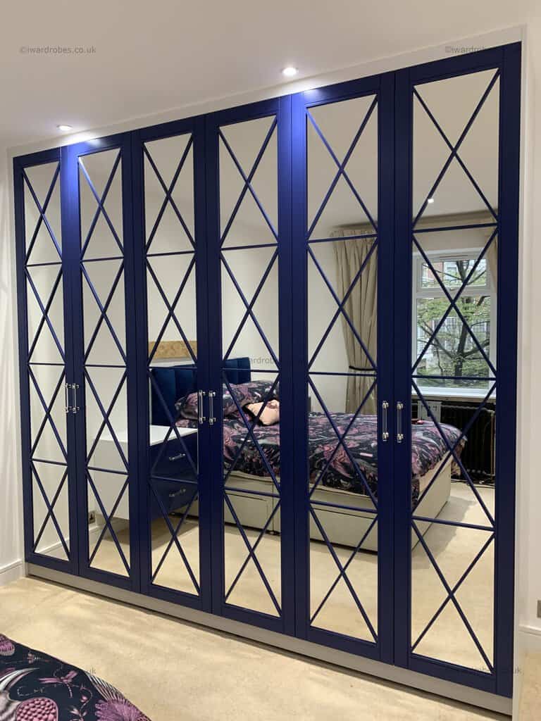 Bespoke navy blue painted fretwork mirror wardrobe with mirrored doors.