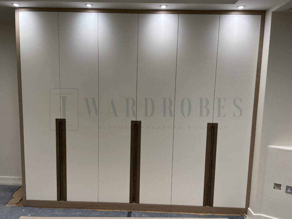 Modern white wardrobe with wooden handles in a contemporary bedroom.
