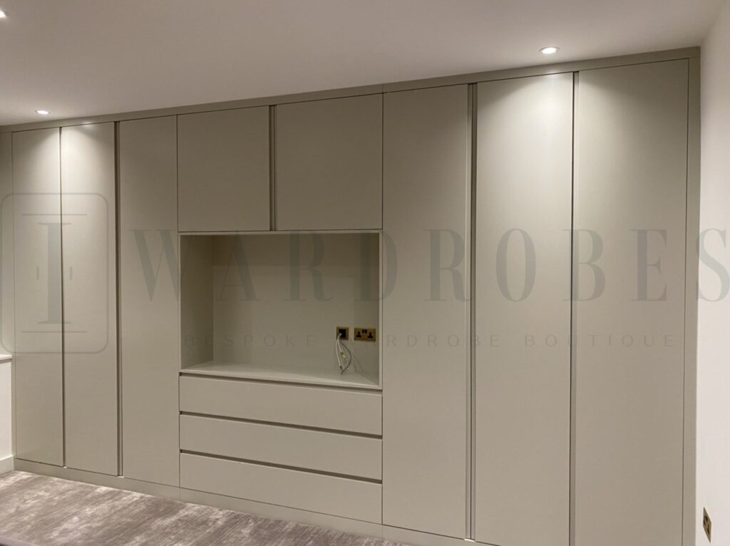 Modern fitted wardrobe with routed handles and spray paint finish in a neutral colour.
