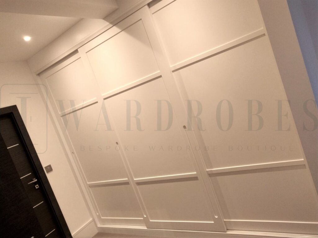 Bespoke spray painted Shaker style sliding door wardrobe in a modern bedroom.