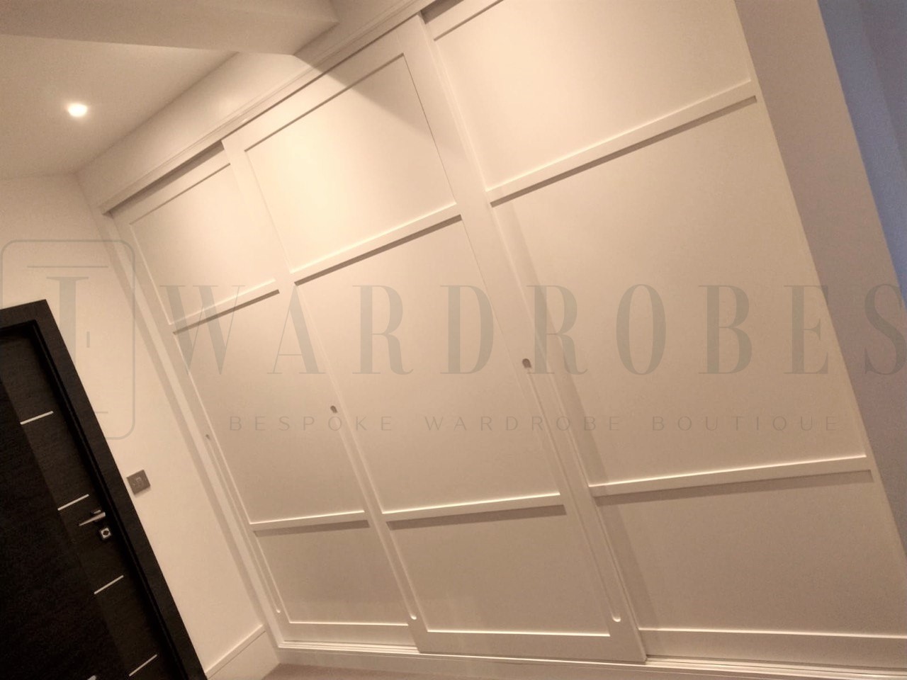 Bespoke spray painted Shaker style sliding door wardrobe in a modern bedroom.