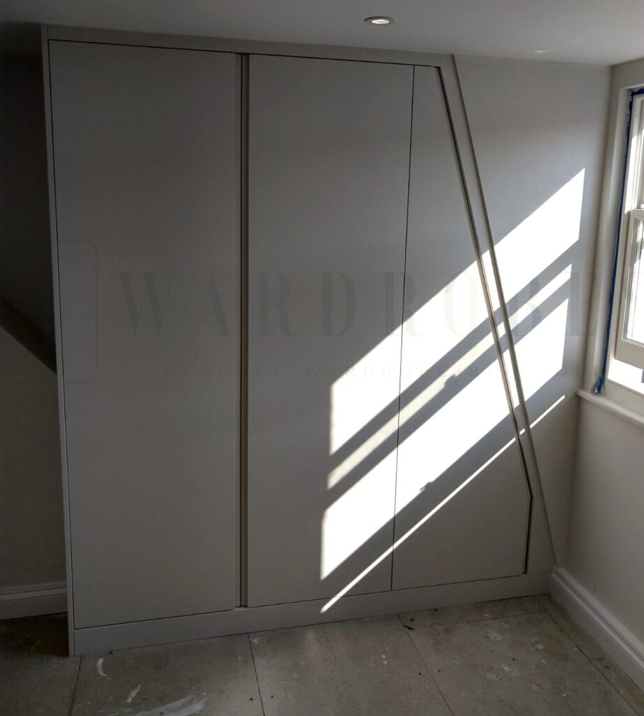 Modern built-in bedroom wardrobe with sloping ceiling design in London home.